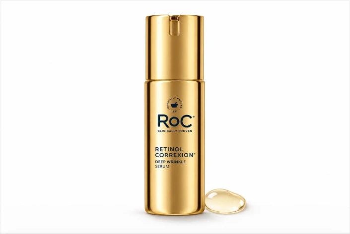 RoC Retinol Correxion Deep Wrinkle Serum in a gold bottle with a serum droplet on a white background.