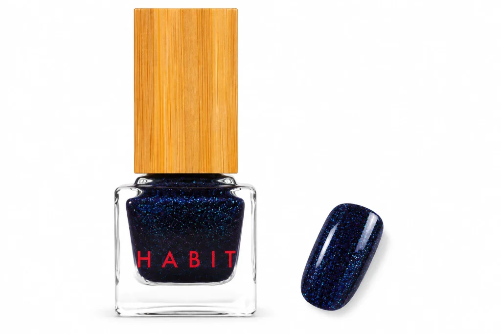 Habit Cosmetics Space Cadet Blue navy shimmer nail polish bottle with one nail painted in the shimmer, one of the best glitter nail polish picks